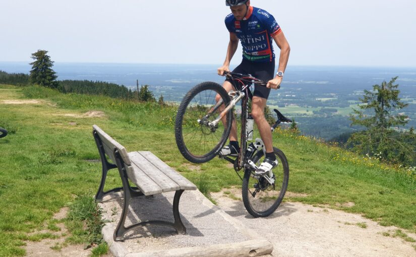 man biking and about to step on gray bench