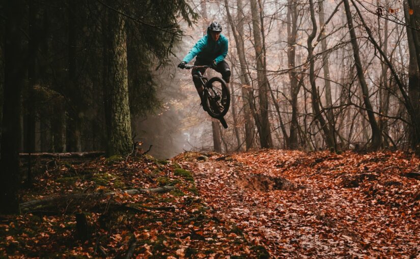 man riding bike over dried leaves on ground