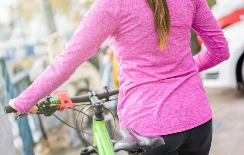 woman in pink long sleeve shirt and black pants riding green bicycle during daytime