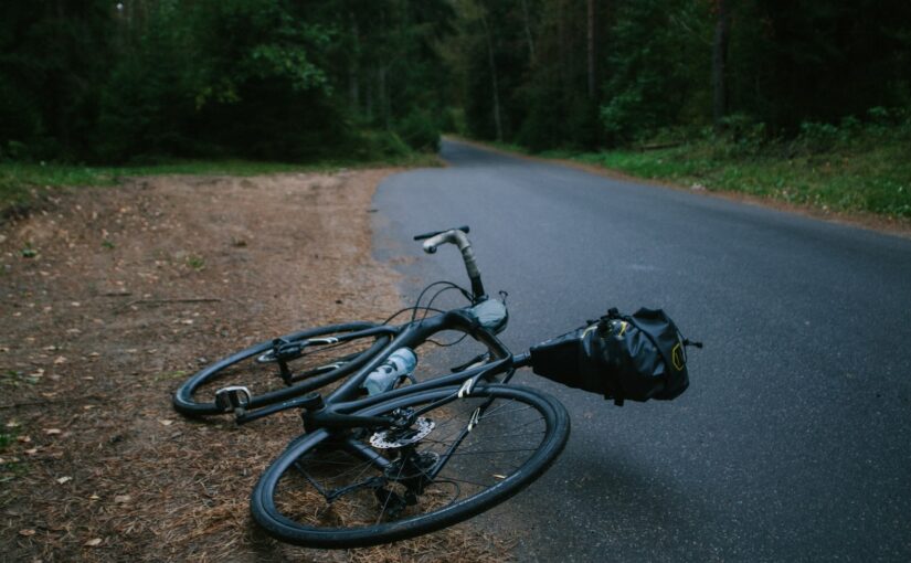 black road bike lying on asphalt road during daytime