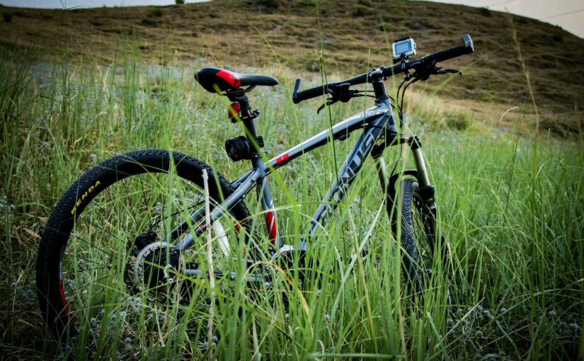 grey and black bicycle parked near grass on hill